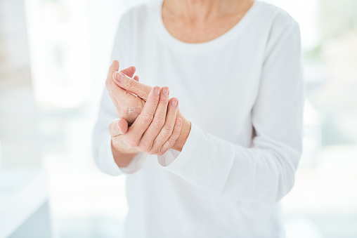 Closeup shot of a mature woman applying hand cream in a bathroom at home